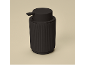 Black soap dispenser with a ribbed texture on a beige background.