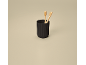 Two bamboo toothbrushes in a ribbed black cup on a beige background.