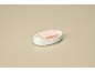 Pink soap in a white ribbed oval soap dish on a beige background.