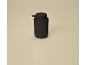 Black soap dispenser with ribbed texture on a beige background.