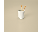 Two bamboo toothbrushes in a white ribbed cup on a beige background.