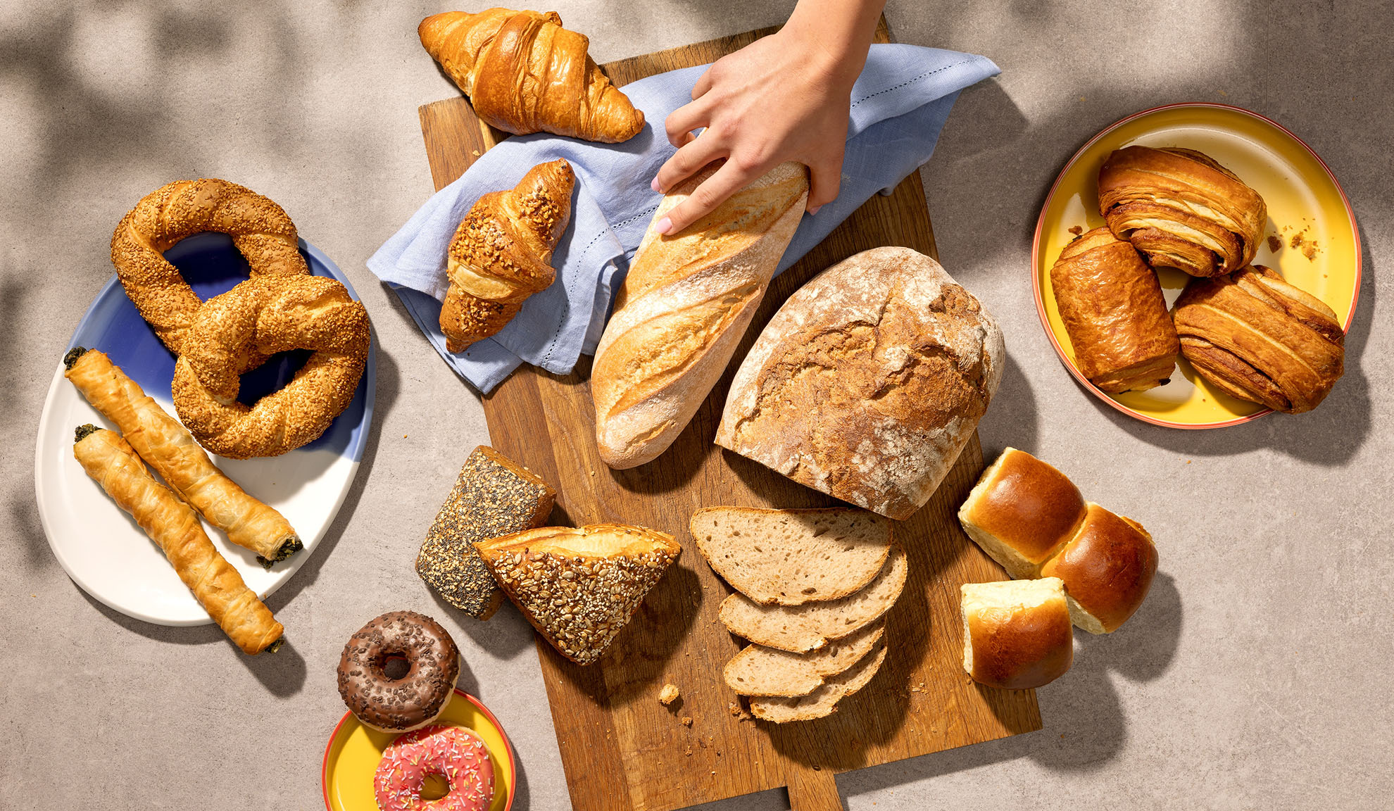 Assortment of fresh baked goods including bread, croissants, pastries, and donuts on a table.