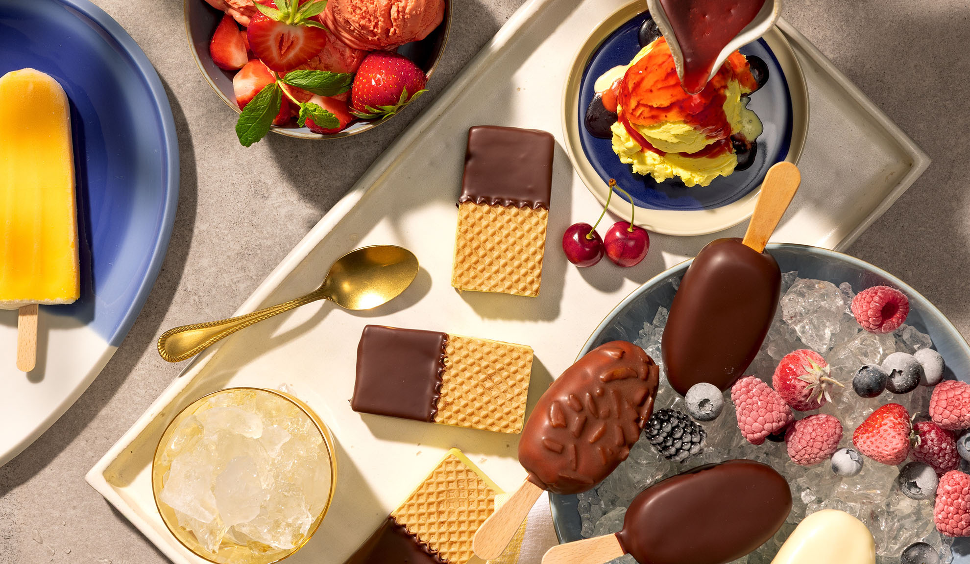 Assortment of ice cream bars, popsicles, waffles, and berries on a tray.