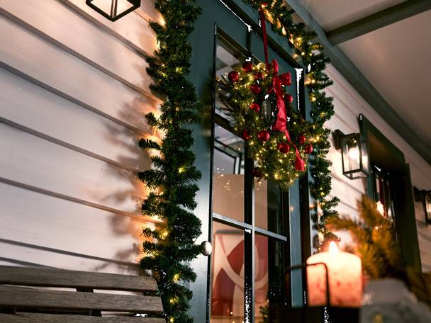 Christmas wreath and garland with lights on a door and wall.
