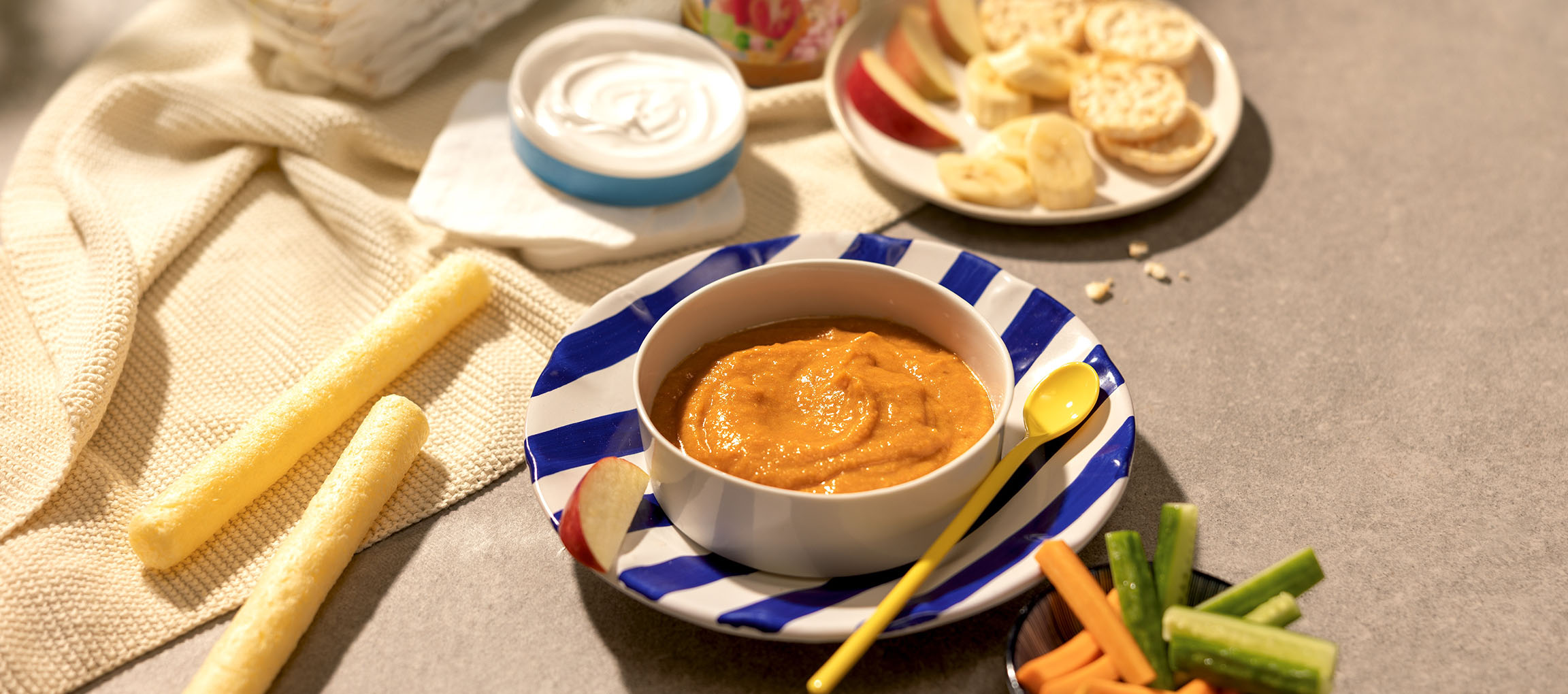 Baby food: bowl of carrot puree, corn sticks, yogurt, fruit, and vegetables.