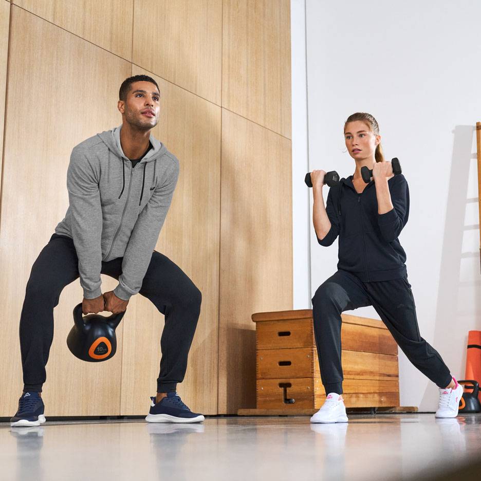 Man and woman in sportswear, working out with a kettlebell and dumbbells.