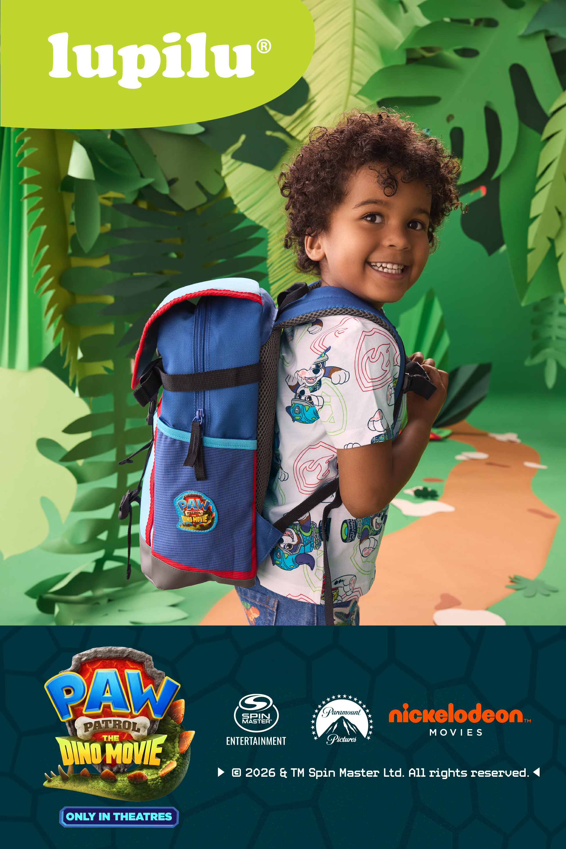 A child wearing a backpack and a Paw Patrol themed shirt, in a jungle-like setting.
