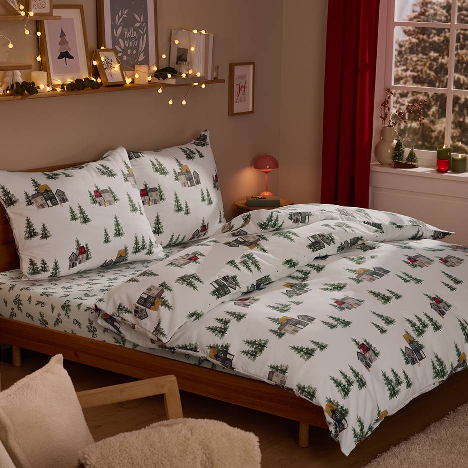 Bedroom with winter village themed bedding, string lights, and Christmas decorations.