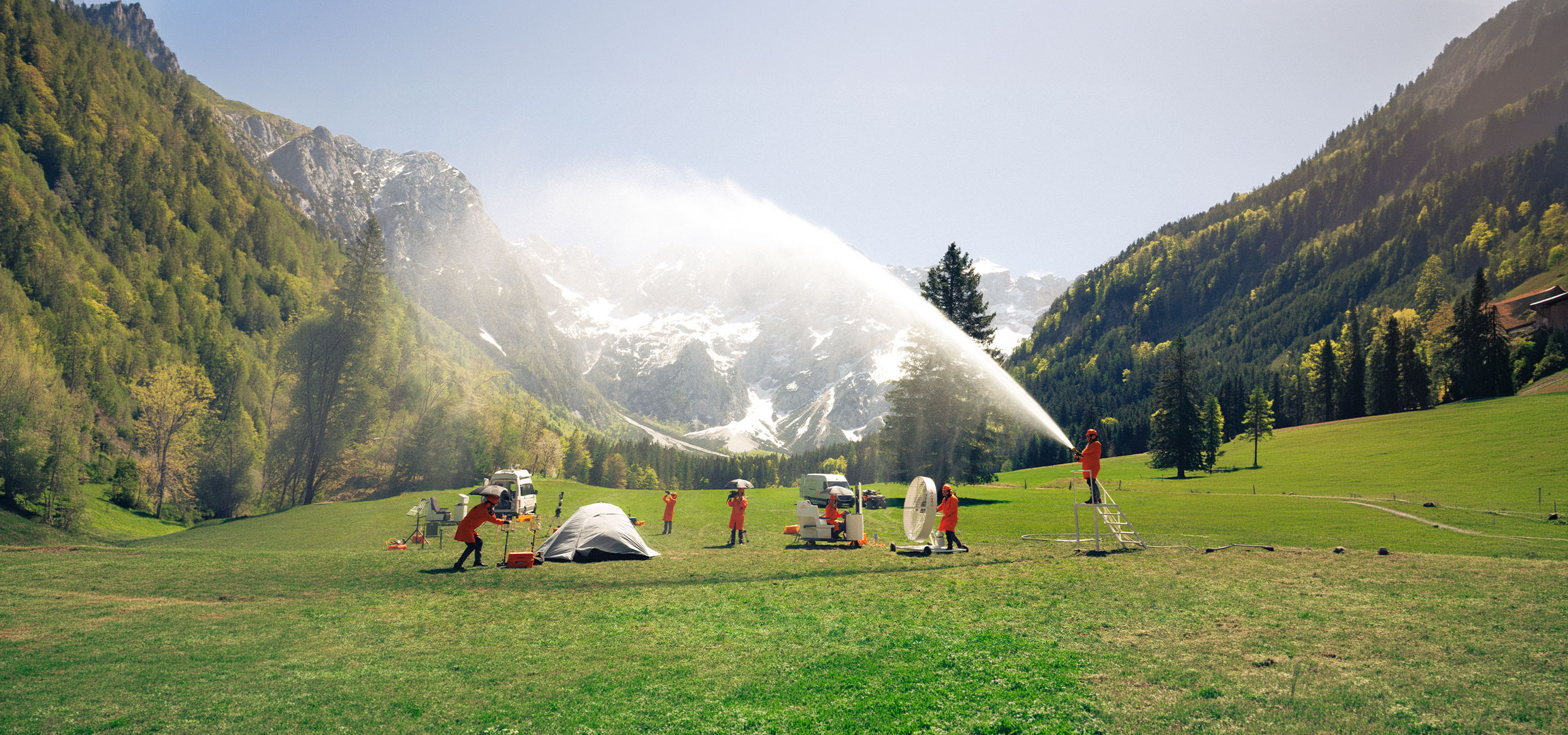 undefined: People in orange protective suits testing camping and outdoor equipment in a meadow.