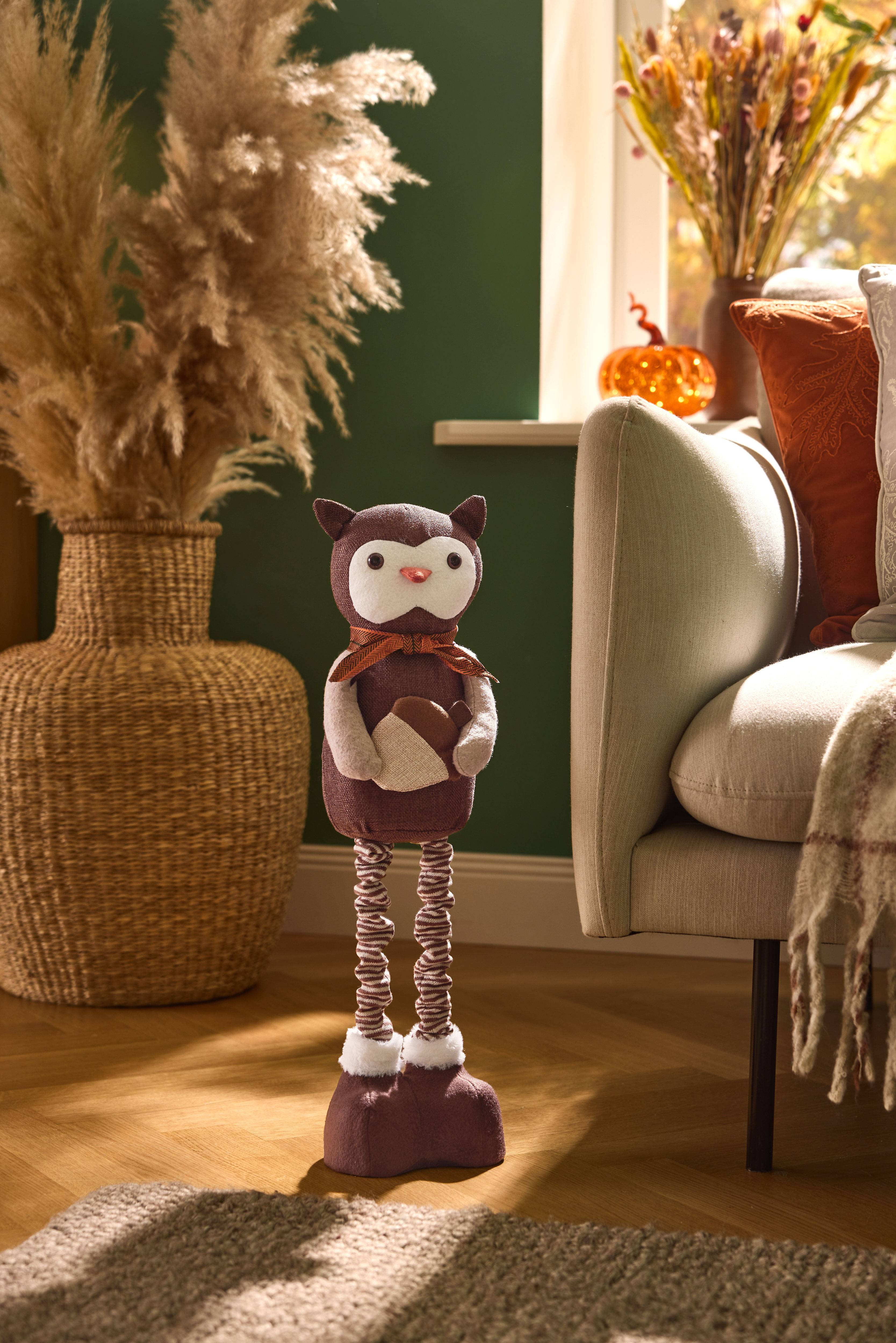 Autumn decoration: owl ornament, dried flowers, and cushions on the sofa.