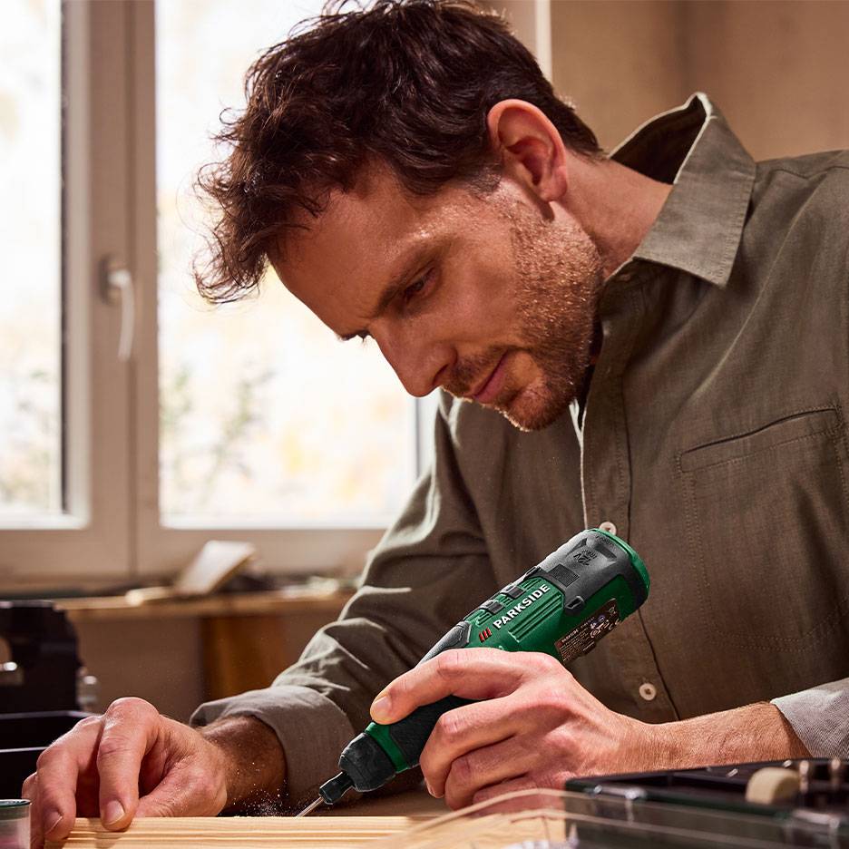 Man using a green electric screwdriver for woodworking.