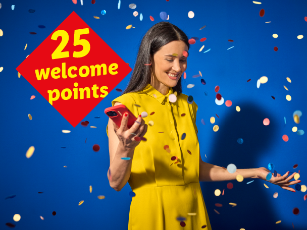 Woman in yellow dress holding a phone, surrounded by confetti, with a red diamond overlay showing '25 welcome points'.
