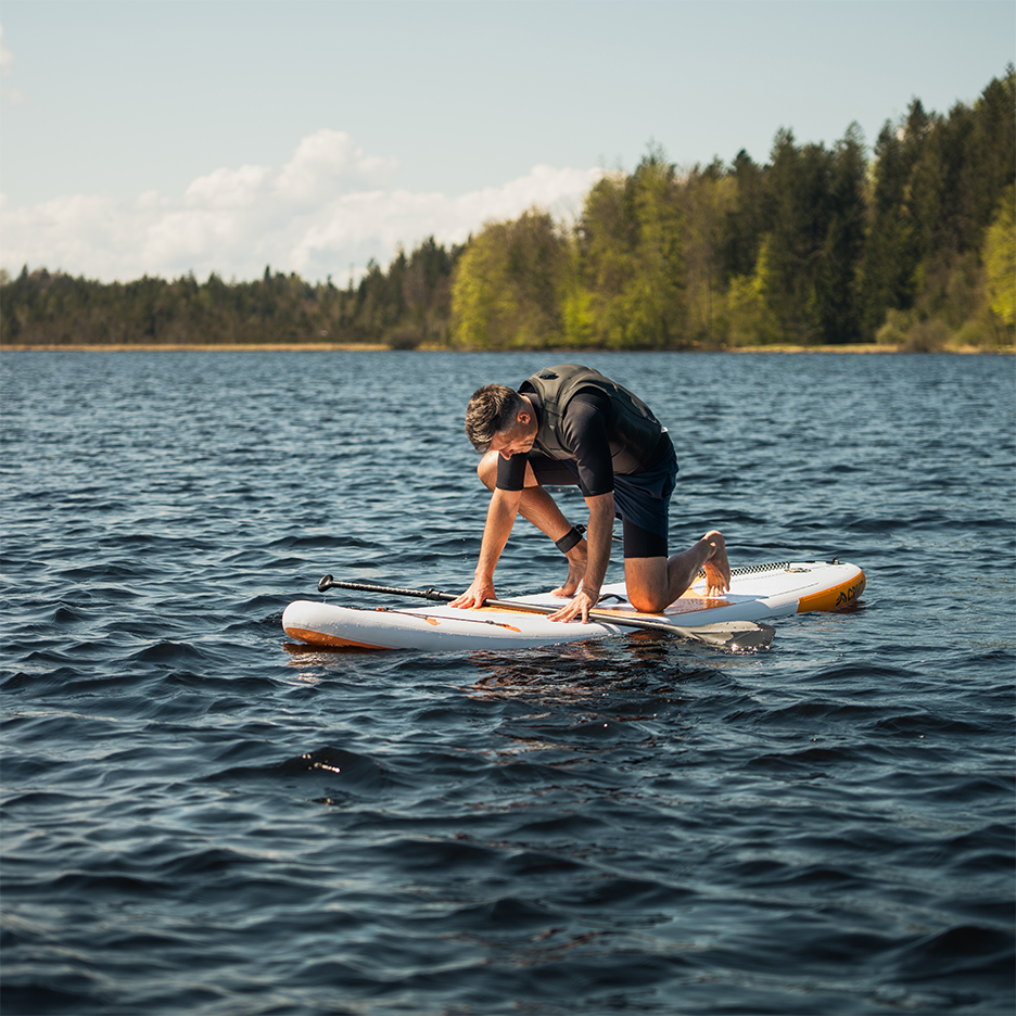 Man på en SUP-bräda i en sjö.