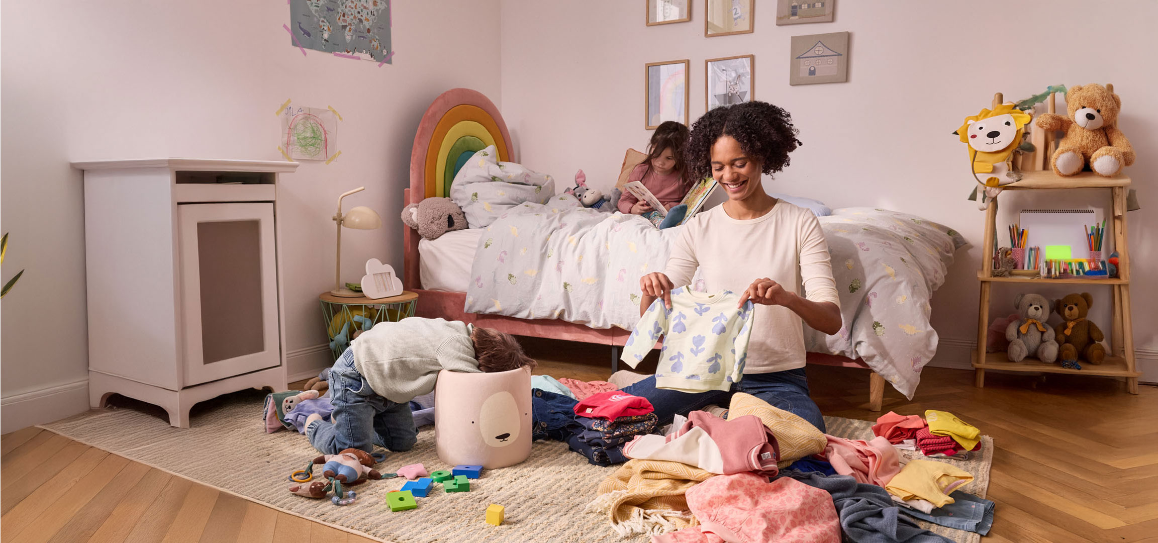 Uma mãe arruma as roupas das crianças em um quarto infantil.