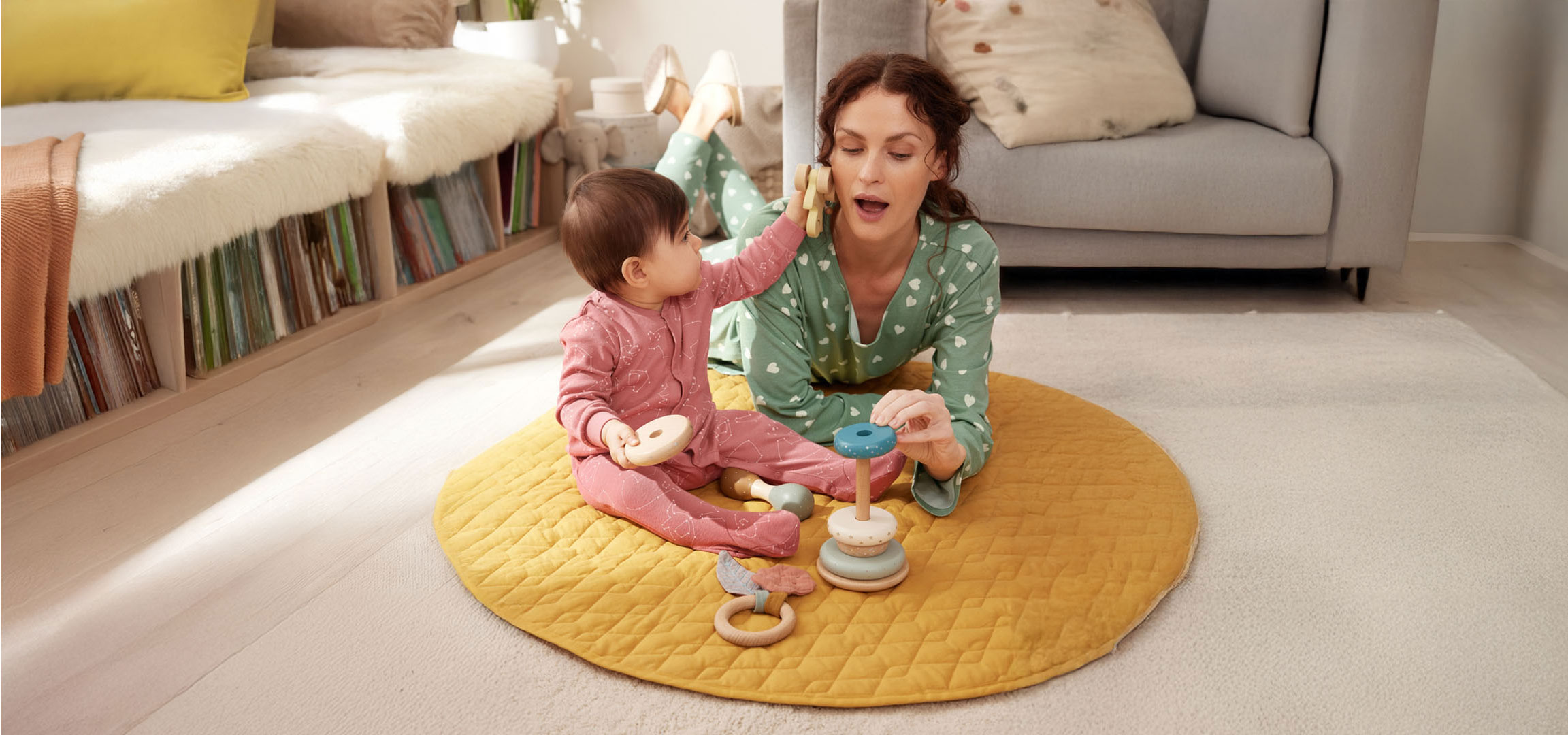 Mãe e bebê brincando com brinquedos no chão.