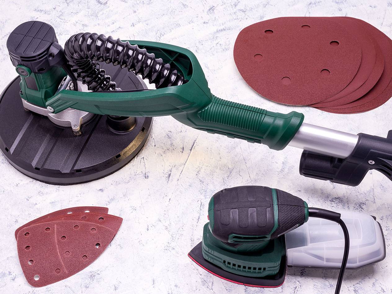Electric sanders with sanding accessories on a light background.
