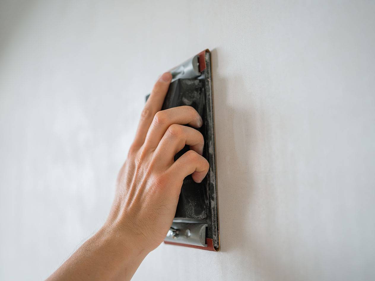 Hand sanding a wall with a sanding block