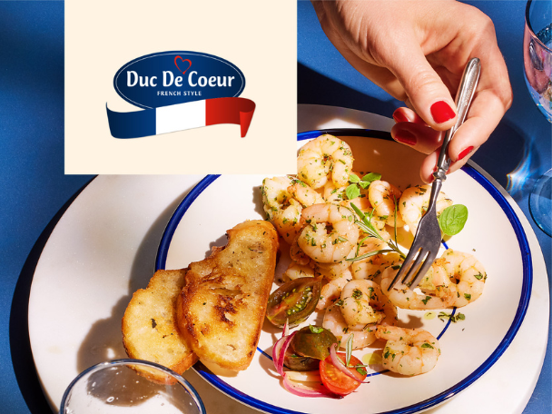 A hand with red nails forks a shrimp from a plate with toasted bread and tomatoes.