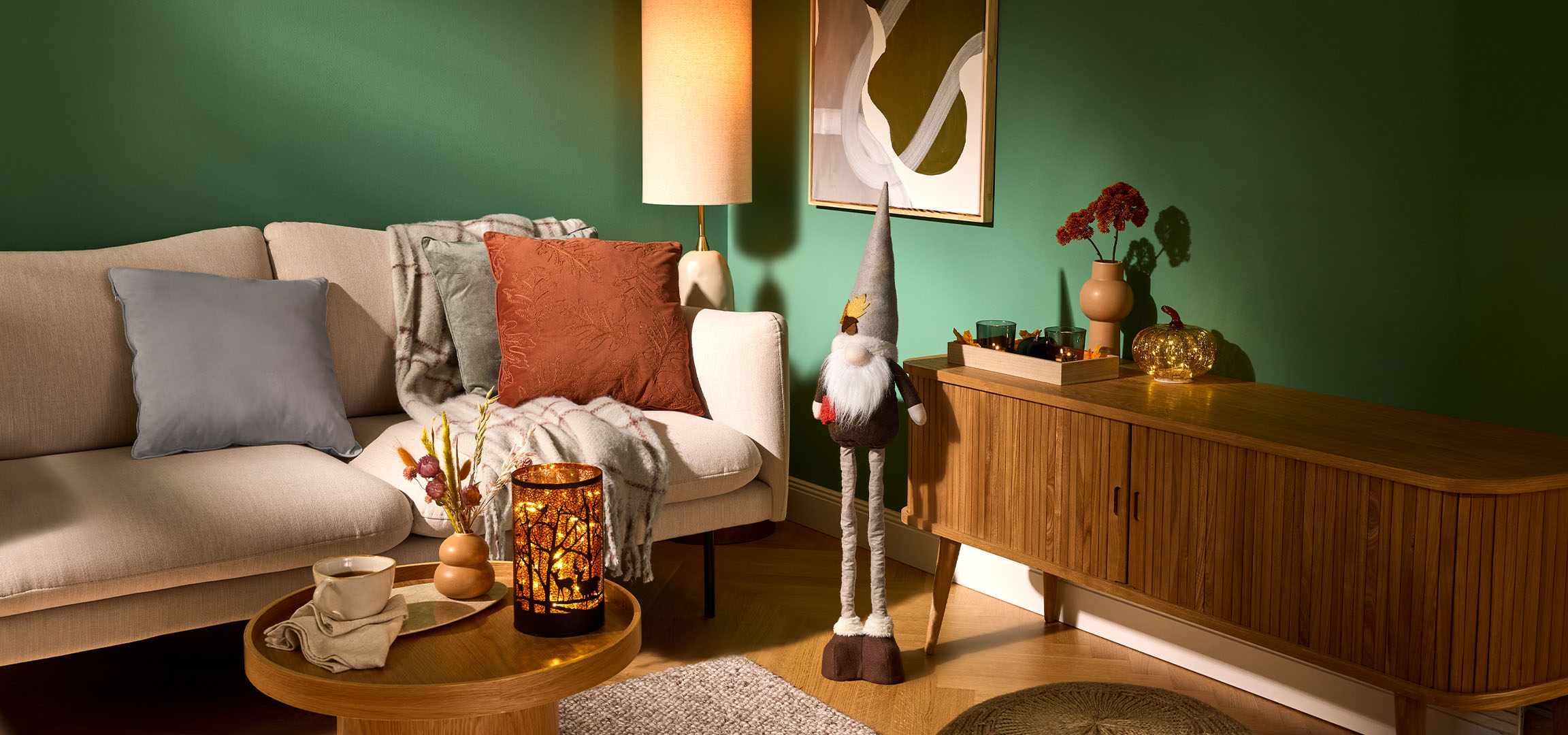 Cozy living room with a beige sofa, cushions, a throw, and autumn decorations.