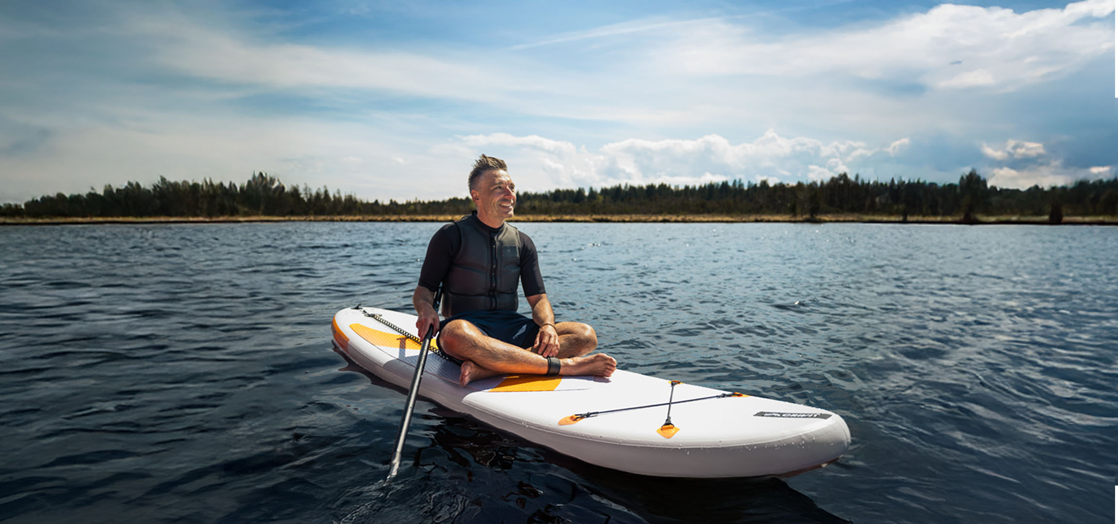 Homem praticando stand-up paddle em um lago.