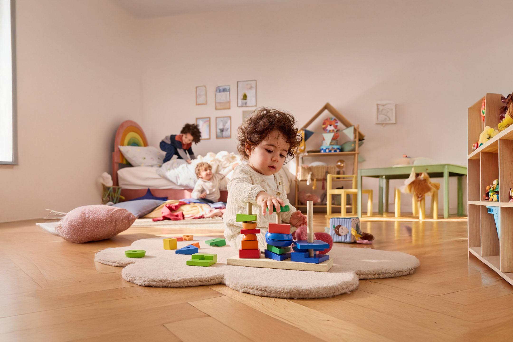 Uma criança pequena brinca com um brinquedo de empilhar de madeira em seu quarto.