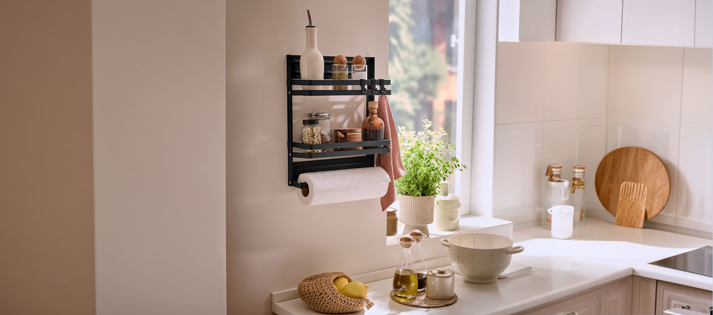 Black wall-mounted spice rack with paper towel holder in a bright kitchen.