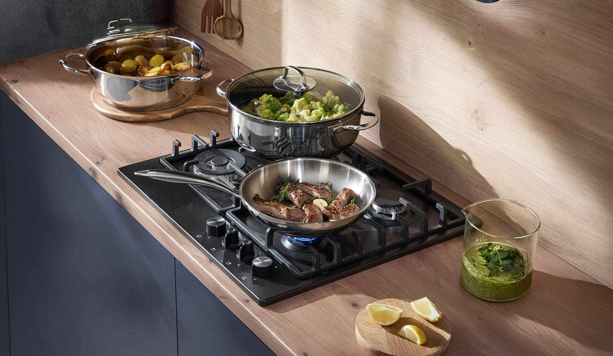 Gas hob with a pan and pots on a wooden countertop, preparing a meal.