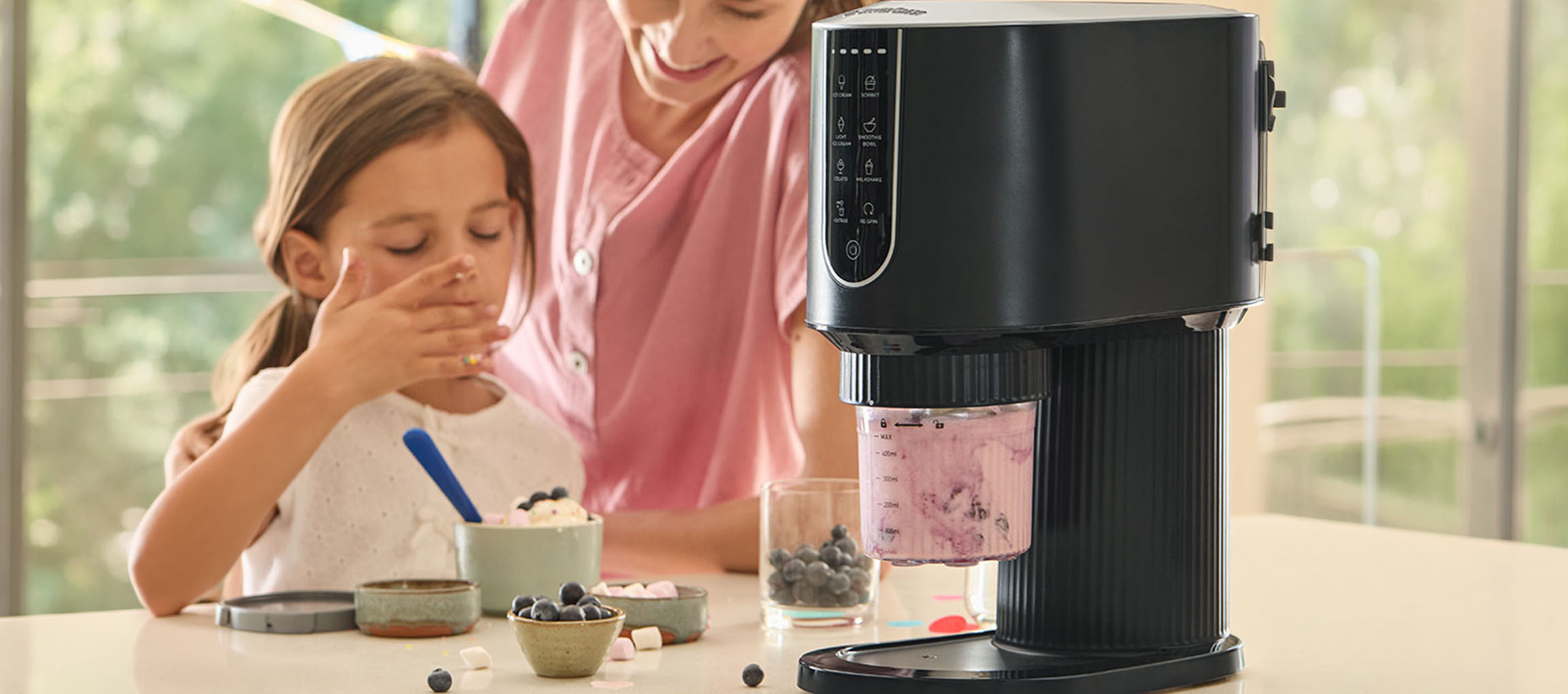 Ice cream maker making berry ice cream, child and adult enjoying the dessert.