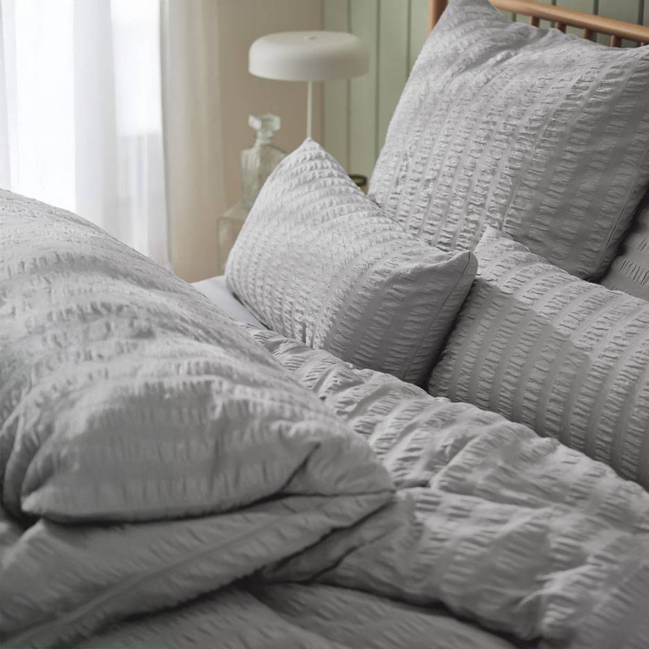 Grå sängkläder med texturerade kuddar.